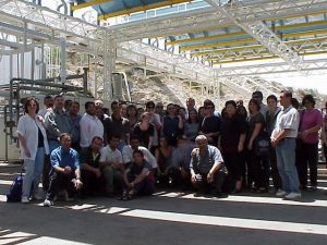 מורים למדעים בעת סיור במפעל על רקע הצד התחתון של המבנה עליו מורכבים הקולטים